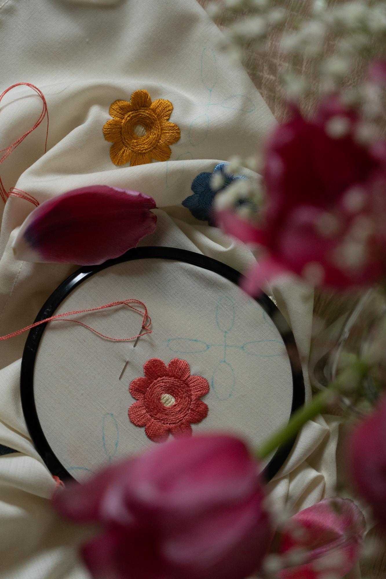 Mano che ricama un fiore su tessuto